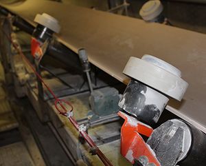 Rouleaux de guidage Optim'RG blancs au bord d'une bande transporteuse en milieu industriel poussiéreux