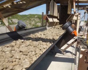 Rouleaux de guidage Optim'RG de part et d'autre d'une bande transporteuse chargée de pierres concassées