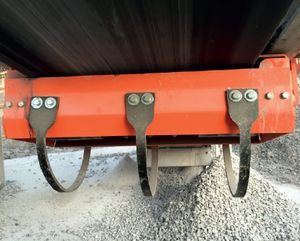 Support orange sous une bande avec trois sangles noires courbes, au-dessus de gravier