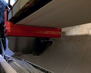 Support rouge-orange sous une bande transporteuse, avec du produit en poudre dans la goulotte